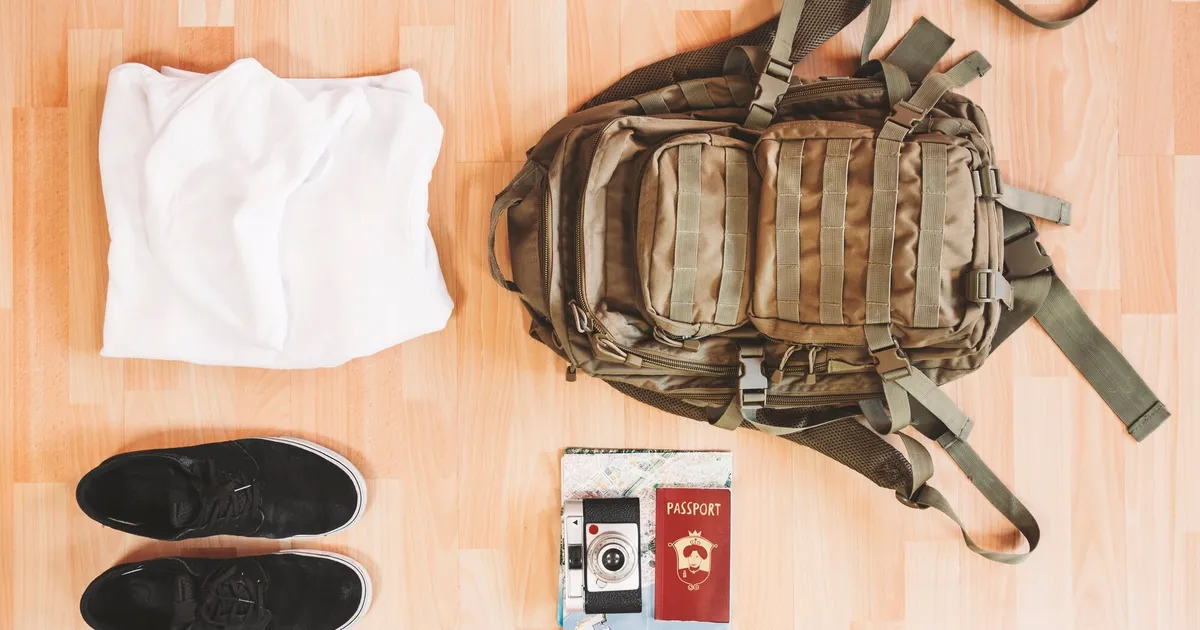 Zaino tattico MOLLE con indumenti, documenti e scarpe pronti per l'evacuazione su pavimento in legno