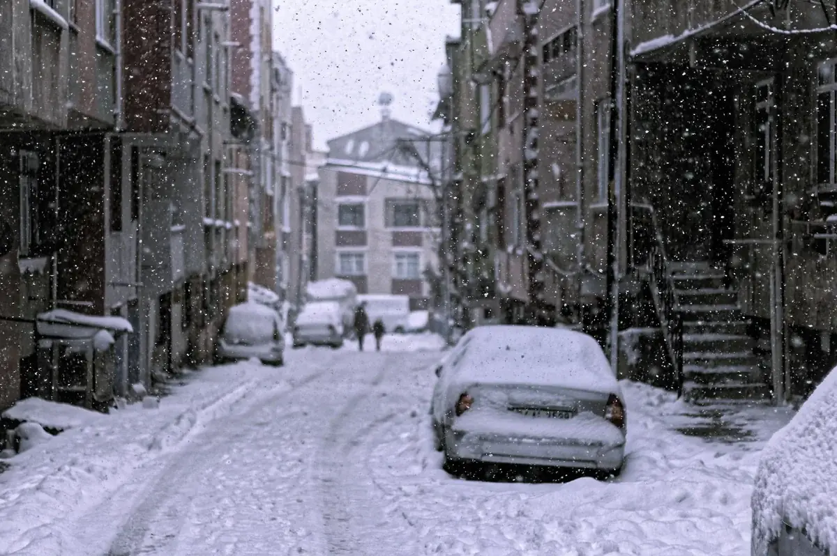 Strada innevata con auto durante una nevicata estrema